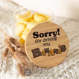 Glass gift jar with UV printed timber lid reading "Sorry for driving you bananas". Styled with banana lollies in the jar on a soft blanket.