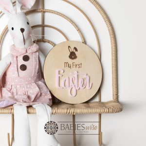 Round timber " My First Easter" plaque with engraved bunny face and 3D acrylic "Easter" lettering. Styled with a soft blanket and woven pillow.