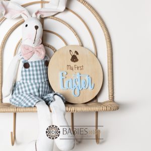 Round timber " My First Easter" plaque with engraved bunny face and 3D acrylic "Easter" lettering. Styled with a soft blanket and woven pillow.