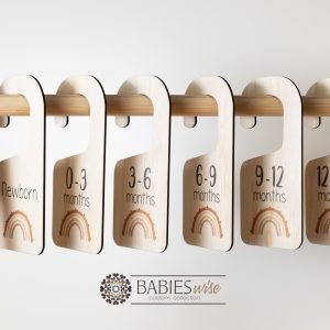 Timber wardrobe divider hangers with brown rainbow design, labelled newborn to 24 months. Styled with divider hangers with baby clothes.