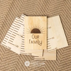 Timber growth chart with five panels and laser engraved header with a sun design with "Our Family" text. Styled with a woven mat.