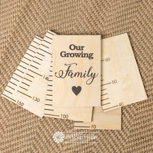 Timber growth chart with five panels and a header with "Our Growing Family" text with black heart. Styled with a woven mat.