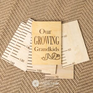 Timber growth chart with five panels and laser engraved header with "Our Growing Grandkids" text with a tape measure design . Styled with a woven mat.