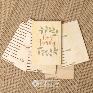 Timber growth chart with five panels and a header "Our Family" texr with green leaf wreath design. Styled with a woven mat.