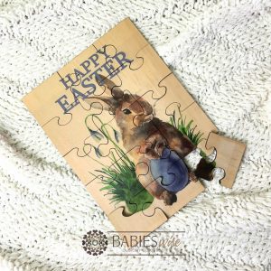 Easrer bunny timber jigsaw puzzle with blue Happy Easter text and blue & purlpe watercolour bunny design . UV printed wooden puzzle for boys. Styled with a soft blanket.