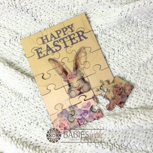 Easrer bunny timber jigsaw puzzle with purple Happy Easter text and pink & purlpe watercolour bunny design . UV printed wooden puzzle for girls. Styled with a soft blanket.