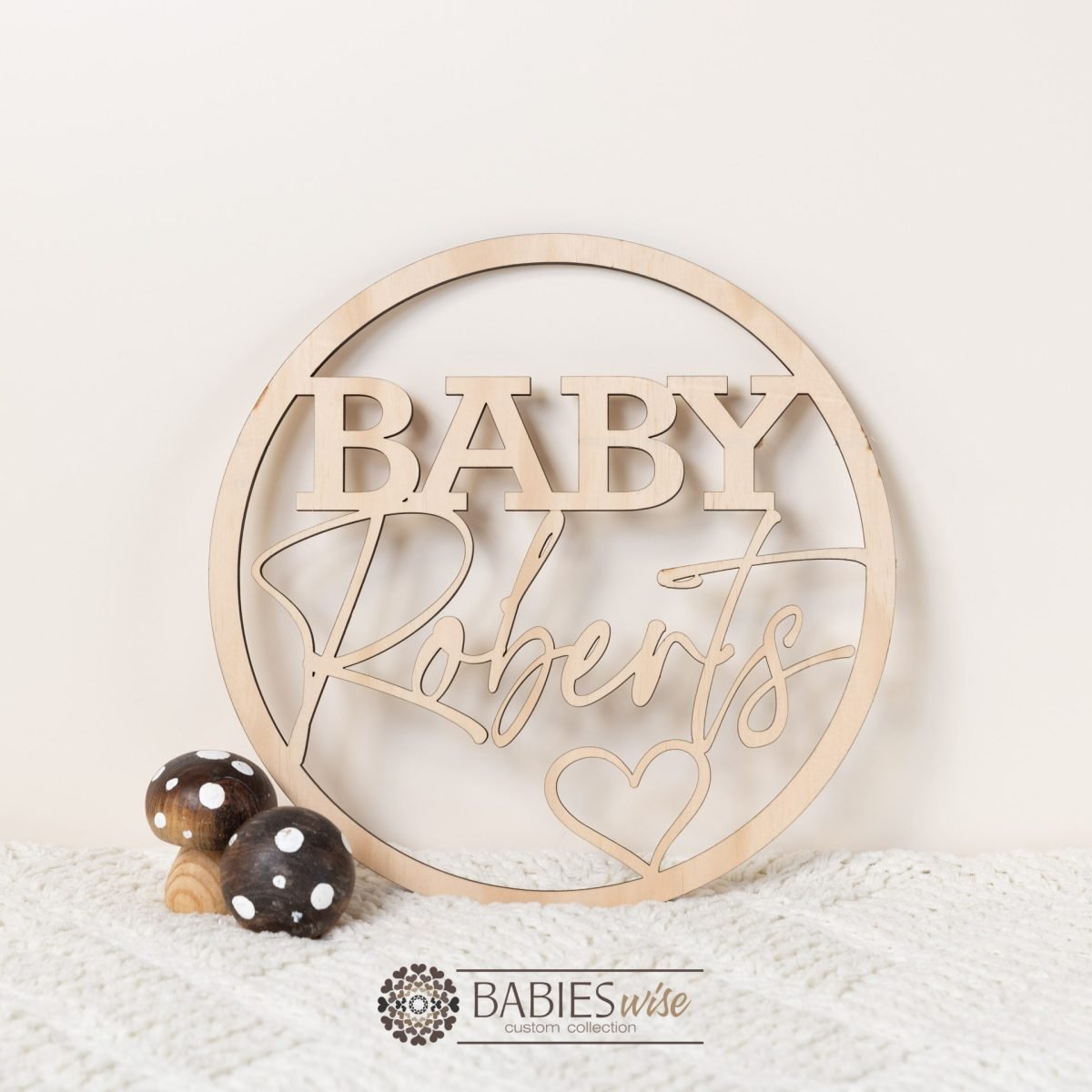 Personlised timber name hoop with bold first "BABY", script surname and heart detail. Styled with a soft blanket and cute wooden mushrooms.
