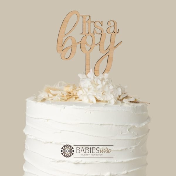 Timber cake topper freaturing the words "Its a Boy" in elegant script lettering. Displayed on a white cake with white flowers.