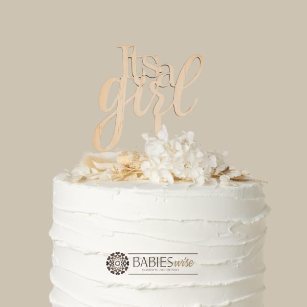 Timber cake topper freaturing the words "Its a Girl" in elegant script lettering. Displayed on a white cake with white flowers.