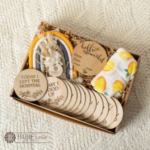 Baby Milestone gift box with timber "Today I" milestone discs, birth announcement plaque, lemon swaddle, macrame and dried flower arrangement. Gift Box styled on a soft blanket.