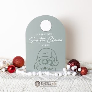Olive acrylic arch Christmas countdown plaque with Santa illustration and wipeable circle for counting sleeps until Santa visits. Styled on a soft blanket with Christmas decorations.