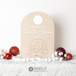 Latte acrylic arch Christmas countdown plaque with Santa illustration and wipeable circle for counting sleeps until Santa visits. Styled on a soft blanket with Christmas decorations.