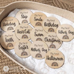 My First baby milestone plaques UV printed on timber discs with rainbow design in Blue or Brown options. Styled on a woven bassinett on a woven neutral mat.