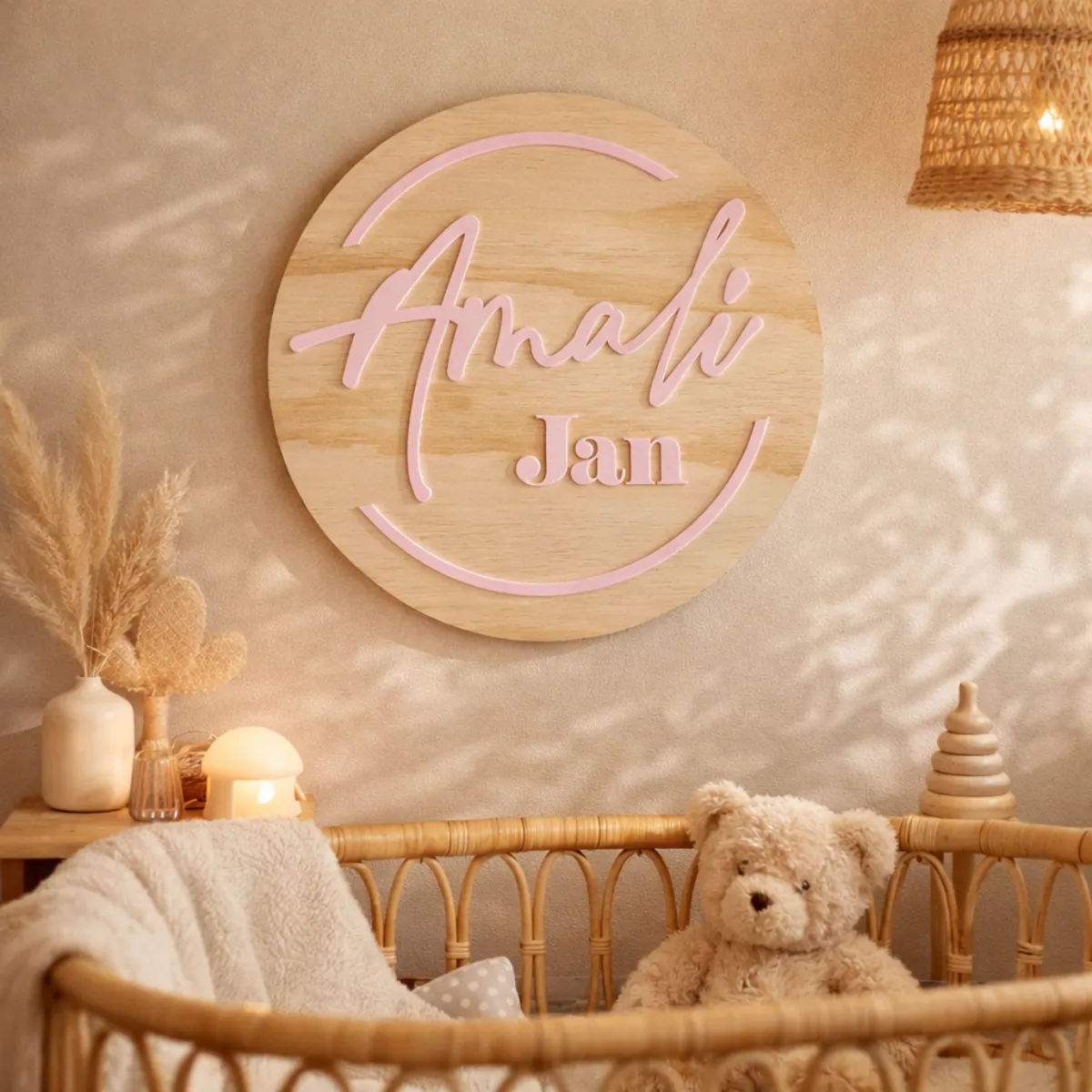 Personlised circular timber nursery name sign with raised 3D acrylic. Styled in a rattan cot in neutral nursery.