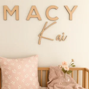 Timber Nursery names sign features block letters for the first name and the middle name is in a flowing script. Styled in a nursery with a soft timber cot.