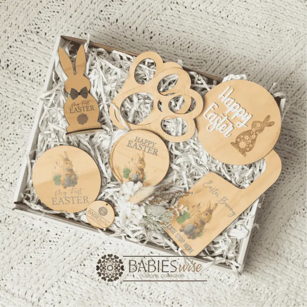 Easter gift box for boys featuring a timber watercolour products, Easter tag, bunny footprint stencil, Happy Easter Plaque, My first Easter plaque, Easter Bunny door hanger, and a Easter jar with a small dried flower arrangement. Presented in a white gift box with shreded paper. Styled on a soft white blanket.