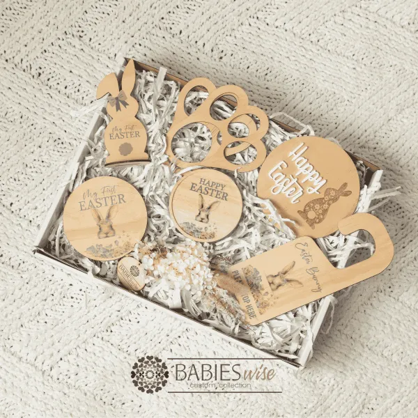Easter gift box for girls featuring a timber watercolour products, Easter tag, bunny footprint stencil, Happy Easter Plaque, My first Easter plaque, Easter Bunny door hanger, and a Easter jar with a small dried flower arrangement. Presented in a white gift box with shreded paper. Styled on a soft white blanket.