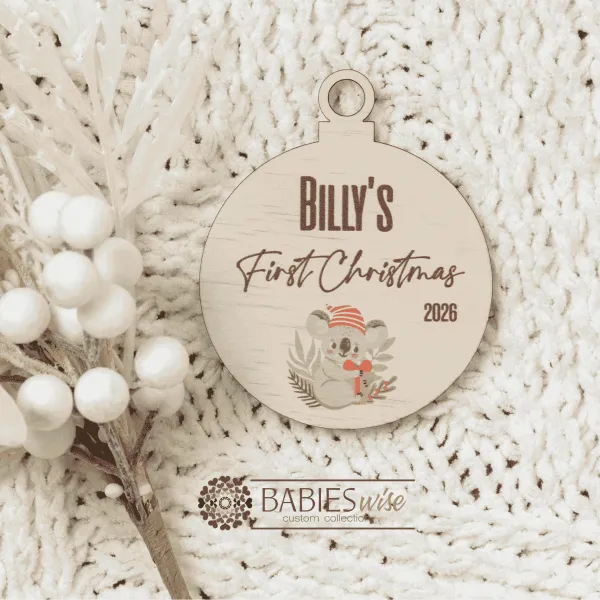 Round timber Christmas bauble UV printed with a selection of designs to choose from and personlised child's name and "First Christmas" with the year. Includes a hole to hang from the Christmas Tree. Style on a warm, soft blanket with a white Christmas wreath.