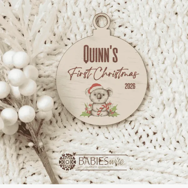 Round timber Christmas bauble UV printed with a selection of designs to choose from and personlised child's name and "First Christmas" with the year. Includes a hole to hang from the Christmas Tree. Style on a warm, soft blanket with a white Christmas wreath.