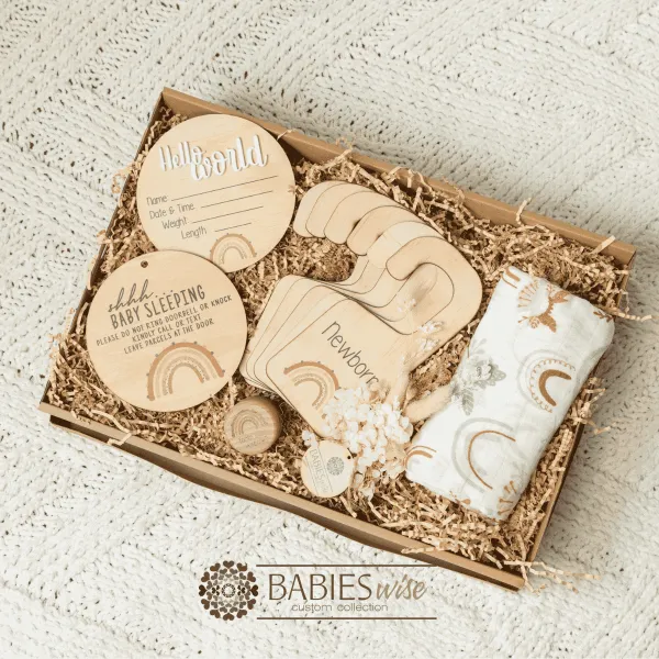 Baby girl keepsake gift box featuring a timber birth announcement plaque, matching "Shh.. Baby Sleeping" plaque, wardrobe dividers, Tooth Fairy Box and swaddle. Styling- Products placed in a Kraft Paper Gift Box with Kraft shredded paper on a soft blanket.