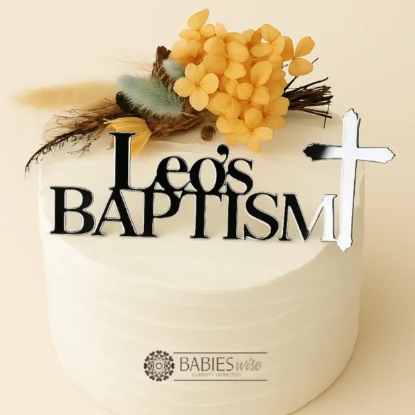 Personlised acrylic Baptism cake fropper featuring the name in bold lettering above the word Baptism with a cross details. Styled on a white cake with a floral arrangement.