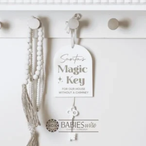 Acrylic arch Christmas hanger UV printed with "santa's Magic Key" and hanging white acrylic key. Includes a hole at the top for hanging with ribbon or string. Styled hanging from a knob with decorative beads.