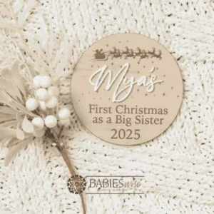 Round timber "My First Christmas as a Biog Sister/Big Brother" plaque featuring Santa's sleigh and reindeers flying across the night sky with stars and snowflakes with 3D acrylic child's name and printed year. Styled on a soft white blankt with a white Christmas wreath.