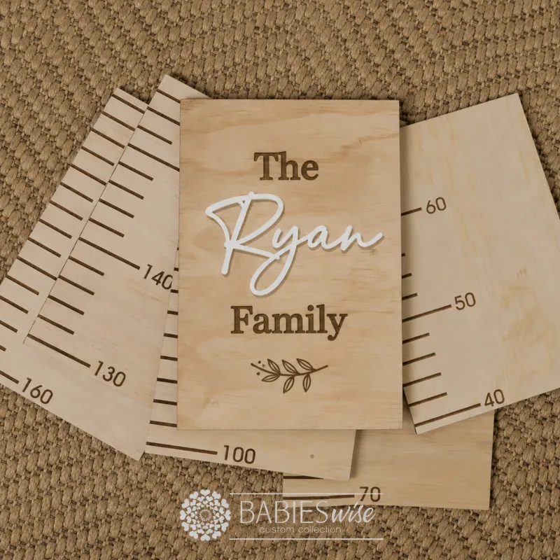 Personlised Timber Growth Charts laser engraved Header with the words- The Surname Family with a leaf and 3D acrylic Surname in script lettering. Styled as a flat-lay photo on a woven mat with the panels.