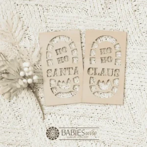 Set of two timber Santa footprint stencils designed to create Christmas Eve boot prints. One stencil features "HO HO Santa Claus" and the other a small "Christmas tree Santa Claus". Styled on a soft white blanket with a white Christmas wreath.