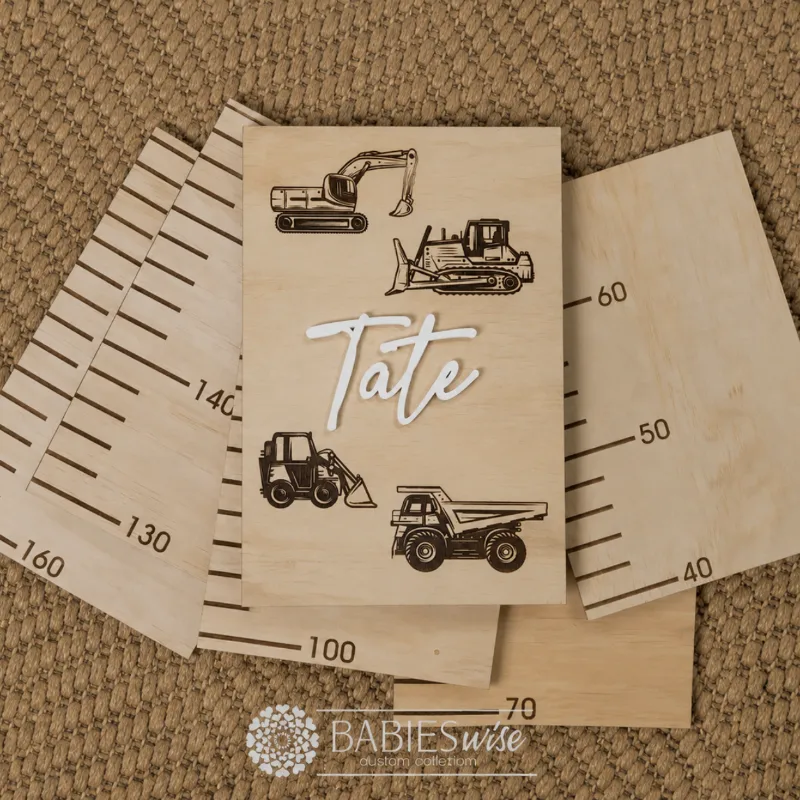 Personlised Timber Growth Charts laser engraved Header with earth moving equipment and 3D acrylic child's name in script lettering. Styled as a flat-lay photo on a woven mat with the panels.