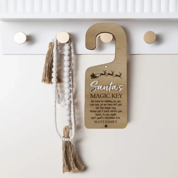 Personlised timber Santa's Magic Key door hanger with 3D acryloc lettering, festive sleigh illustration, anda removable magic key. Styled hanging from a knob with decorative beads.